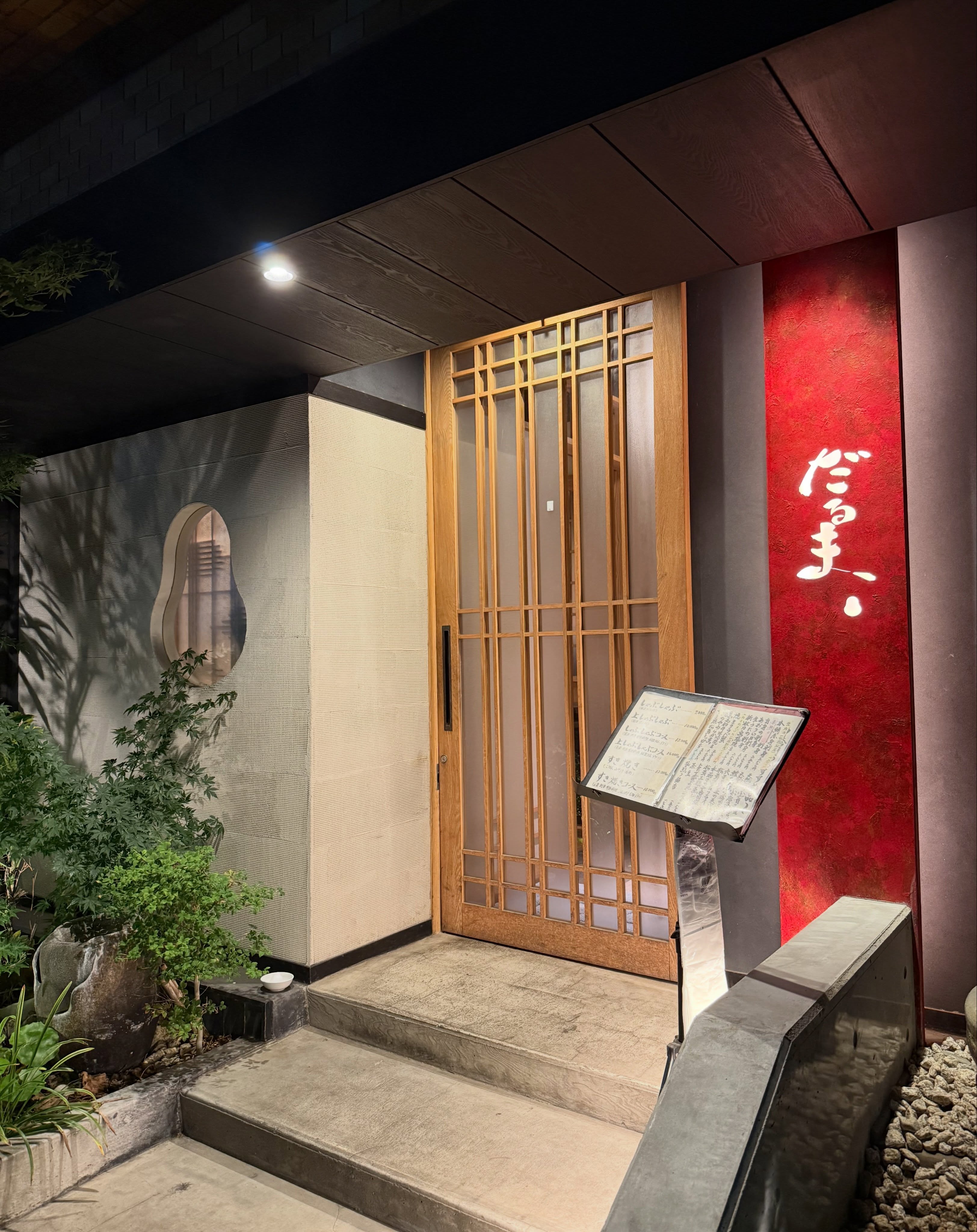 赤いだるまの看板と木の格子戸がある入口